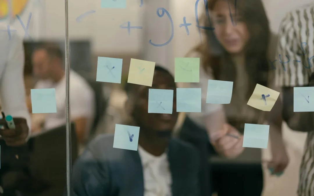 Team collaborating with sticky notes on a glass wall during a strategy session