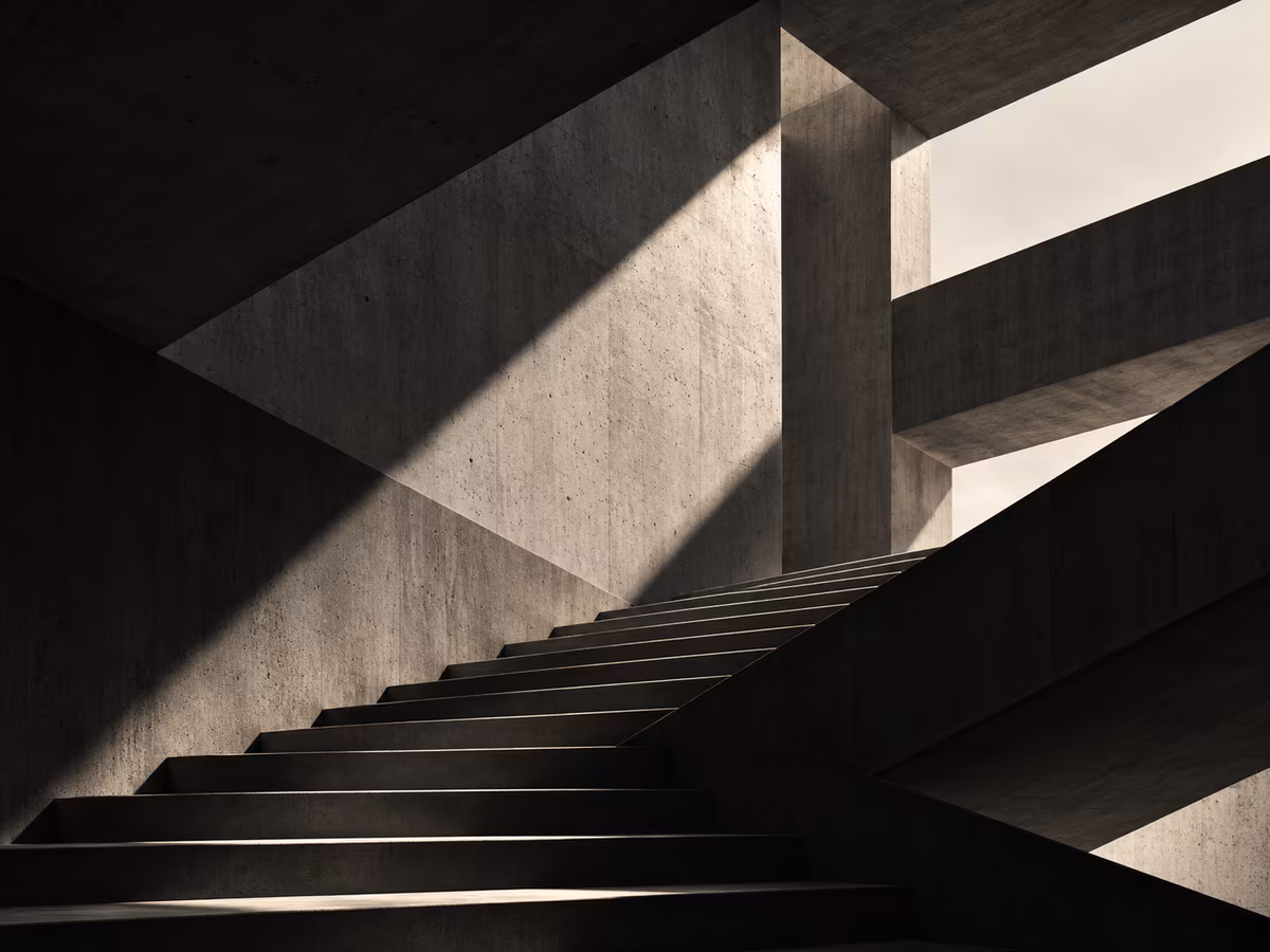 Geometric concrete architecture with intersecting structures, stairs and dramatic shadows.