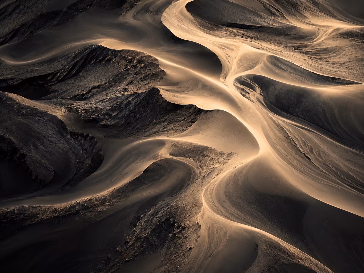 Flowing sand formations with contrasting light and shadow, creating organic patterns.